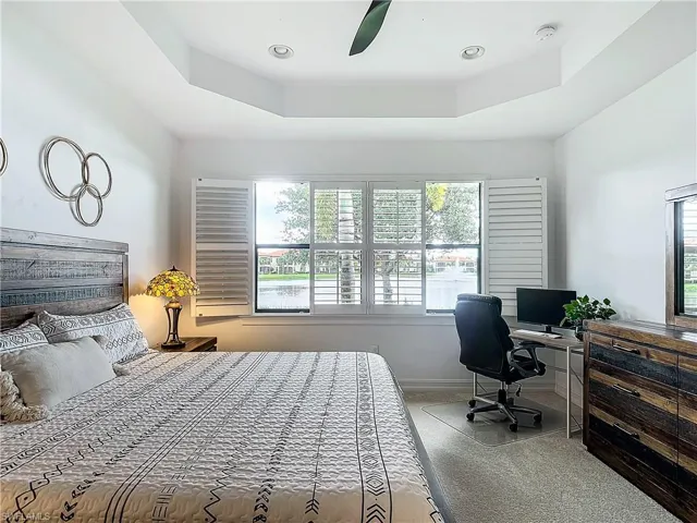 Bedroom with carpet, ceiling fan, and a tray ceiling