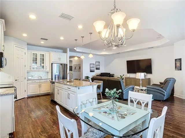 Dining space featuring sink, a chandelier, dark hardwood / wood-style floors, and a raised ceiling