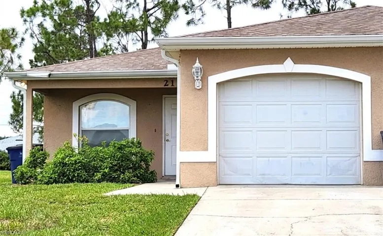 View of front facade featuring stucco siding, a shingled roof, concrete driveway, a garage, and a front lawn