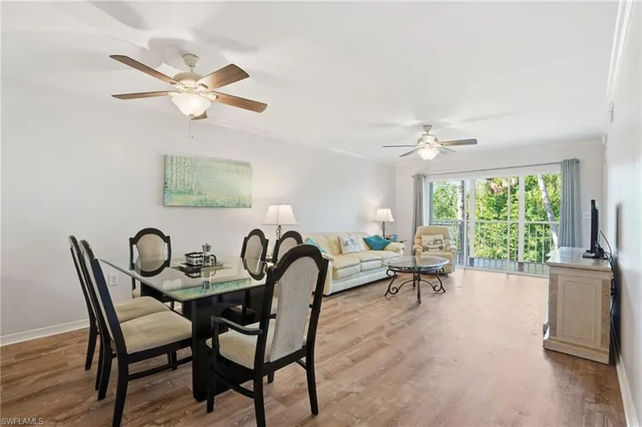 Open Dining/living room area featuring molding, wood finished floors, and a ceiling fan