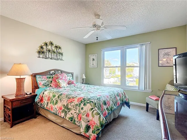 Carpeted bedroom with a ceiling fan and a textured ceiling