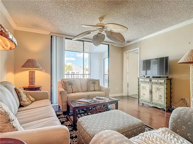 Living room with a ceiling fan, crown molding, a textured ceiling, and wood finished floors