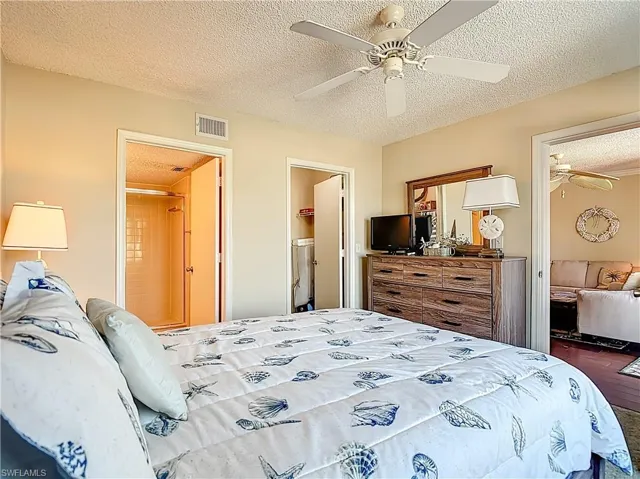 Bedroom featuring a textured ceiling, connected bathroom, and a ceiling fan