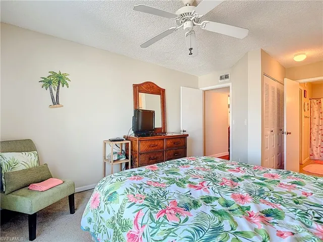 Carpeted bedroom featuring a ceiling fan and a textured ceiling
