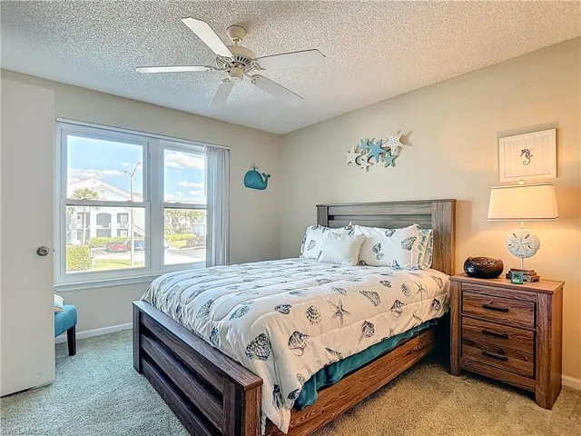Bedroom with light carpet, ceiling fan, and a textured ceiling
