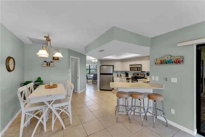Kitchen featuring stainless steel appliances, an inviting chandelier, a kitchen breakfast bar, kitchen peninsula, and light tile patterned flooring