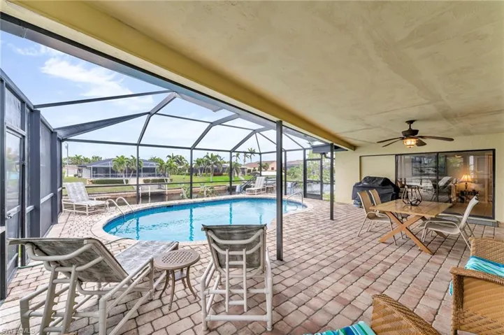 View of swimming pool featuring a patio area, a lanai, ceiling fan, and area for grilling