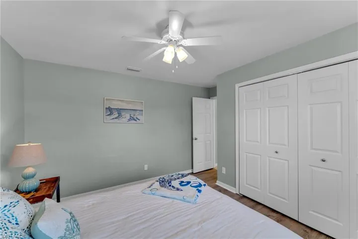 Bedroom with ceiling fan, dark wood-type flooring, and a closet