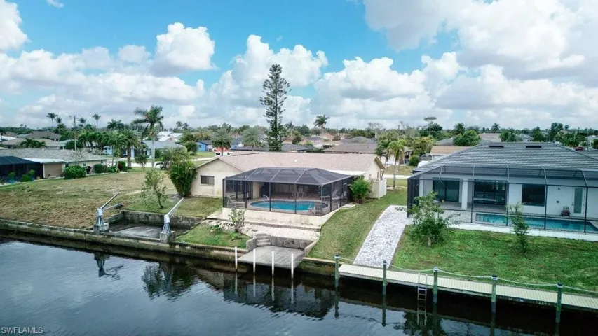 Back of property with a lanai, a yard, and a water view