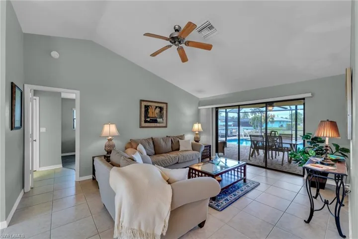 Living room with ceiling fan, light tile patterned floors, and vaulted ceiling