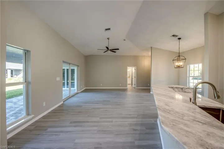 Unfurnished living room with light wood finished floors, lofted ceiling, a chandelier, and ceiling fan