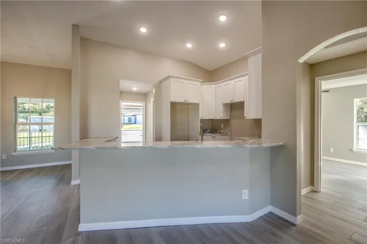 Kitchen with light stone counters, white cabinetry, plenty of natural light, a peninsula, and recessed lighting
