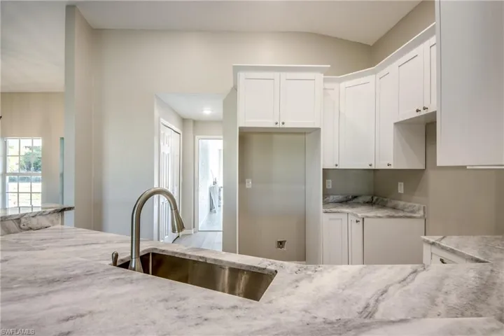 Kitchen with light stone counters and white cabinetry