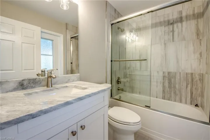 Bathroom with combined bath / shower with glass door and vanity