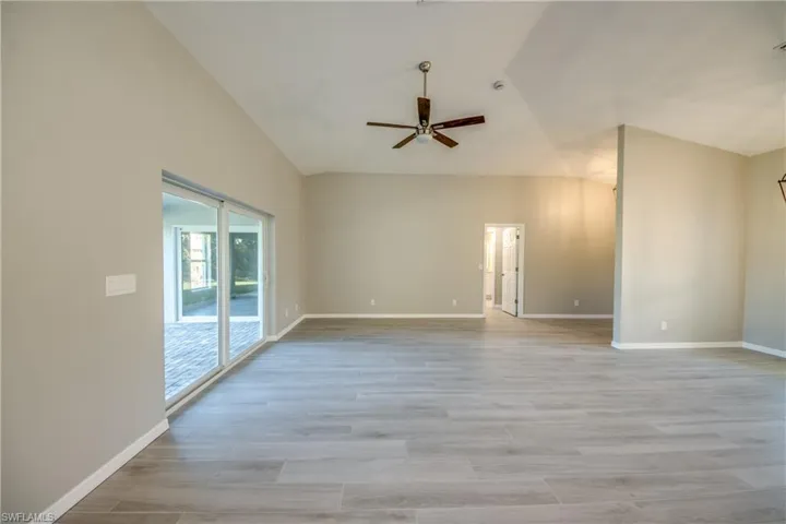 Spare room featuring light wood-style flooring, vaulted ceiling, and a ceiling fan