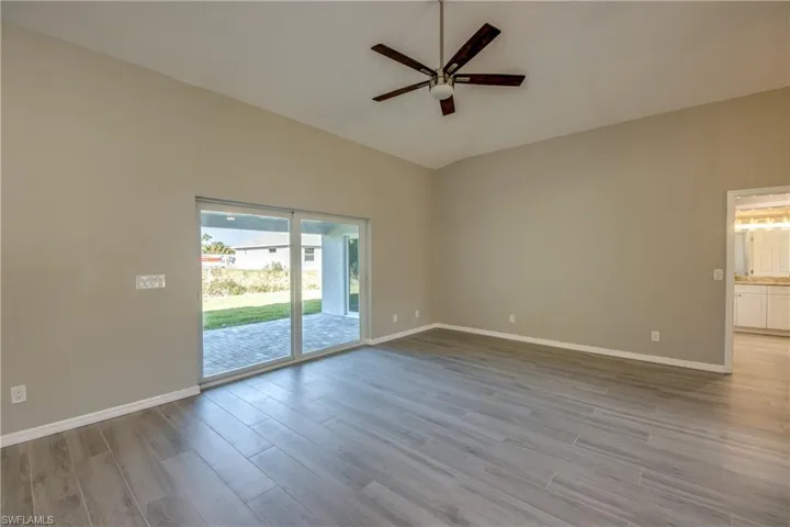 Unfurnished room with light wood finished floors, a ceiling fan, and lofted ceiling