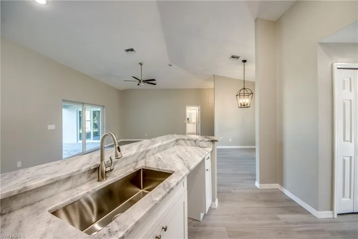 Kitchen with light stone countertops, white cabinetry, decorative light fixtures, and ceiling fan