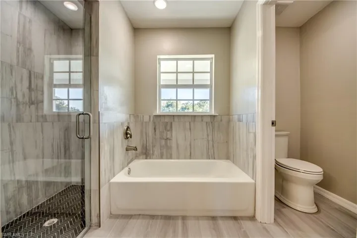 Full bath featuring a bath, a stall shower, and wood finished floors