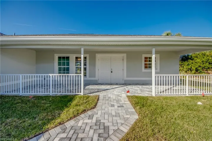 Doorway to property featuring stucco siding, a lawn, and covered porch