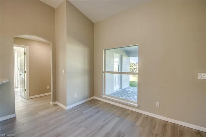 Unfurnished room featuring arched walkways and light wood-style flooring
