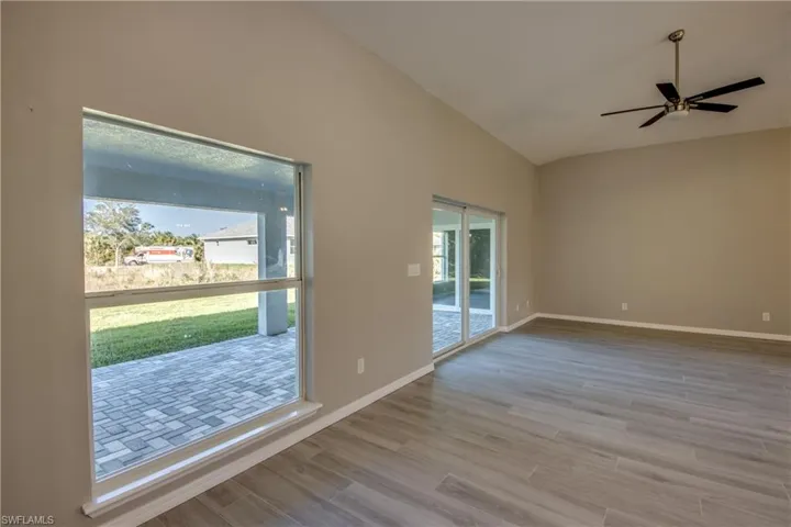 Empty room with vaulted ceiling, light wood finished floors, and a ceiling fan