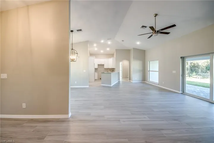 Unfurnished living room featuring light wood finished floors, vaulted ceiling, and ceiling fan