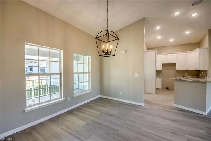 Unfurnished dining area featuring a chandelier, light wood-style floors, recessed lighting, and vaulted ceiling