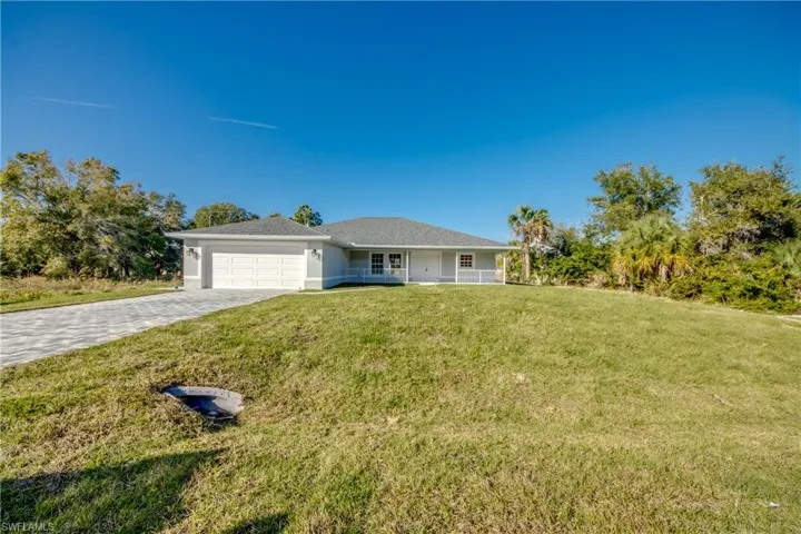 Ranch-style home featuring a front yard, a garage, decorative driveway, and covered porch