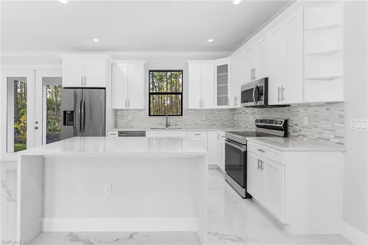 Kitchen featuring stainless steel appliances, white cabinets, sink, tasteful backsplash, and light tile floors