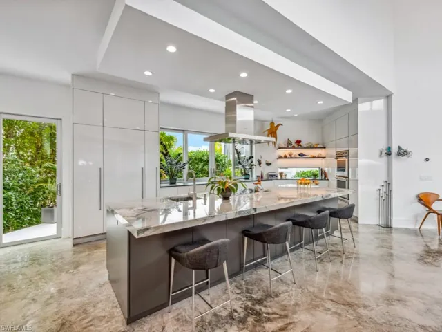 Kitchen with island range hood, sink, a breakfast bar area, a large island, and light stone countertops