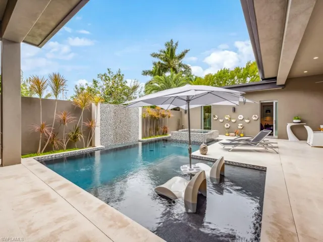 View of swimming pool featuring a patio, pool water feature, and an in ground hot tub