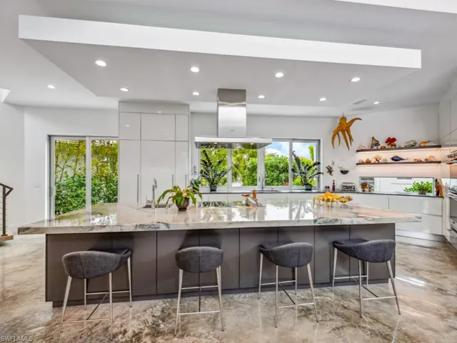 Kitchen featuring a kitchen breakfast bar, a spacious island, light stone counters, white cabinets, and island exhaust hood
