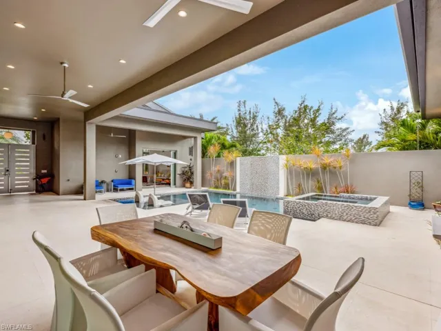 View of patio featuring ceiling fan and a pool with hot tub