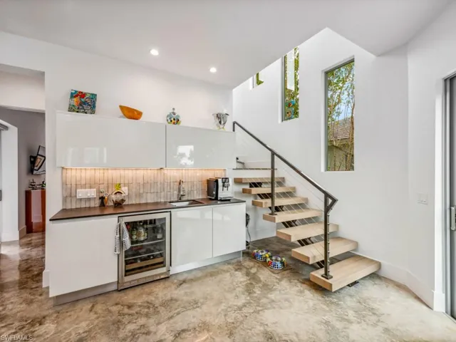 Bar featuring white cabinetry, sink, beverage cooler, and decorative backsplash