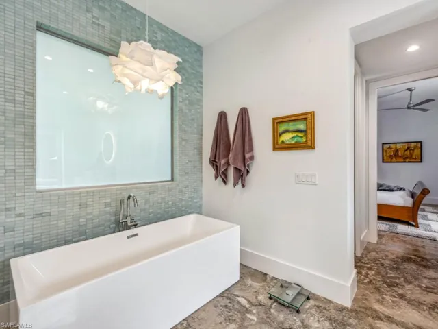 Bathroom featuring ceiling fan and a tub to relax in