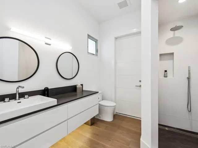 Bathroom featuring hardwood / wood-style flooring, vanity, a shower, and toilet
