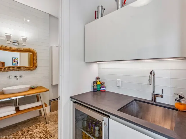 Kitchen featuring beverage cooler, sink, and white cabinets
