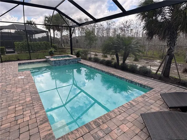Relaxing pool / spa featuring glass enclosure, a patio area, and a sunroom