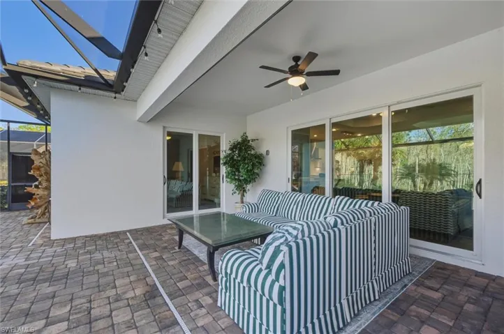 View of panoramic-screened lanai featuring pavers, sliding doors, side screen door and a ceiling fan