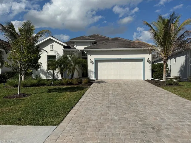 View of front of house featuring a garage, decorative driveway, stucco siding, and a front yard