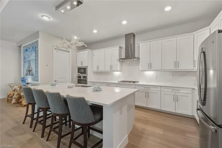 Kitchen with modern lighting, GE appliances with stainless steel finishes, a breakfast bar, walk-in pantry,  white cabinetry, tasteful backsplash, and recessed lighting