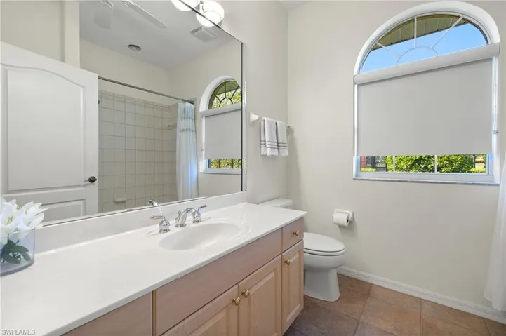 Bathroom featuring a shower with shower curtain, vanity, and toilet