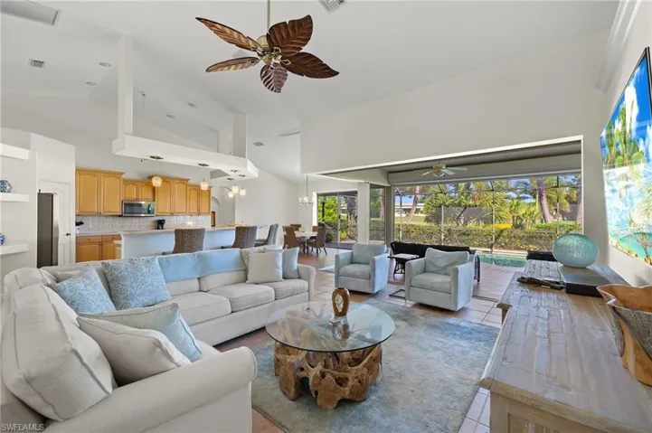 Living room featuring light tile patterned floors, high vaulted ceiling, and ceiling fan