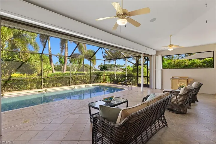 View of swimming pool with glass enclosure, ceiling fan, a patio, and an outdoor living space