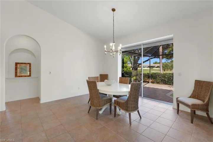 Dining space with light tile patterned floors, lofted ceiling, and a notable chandelier
