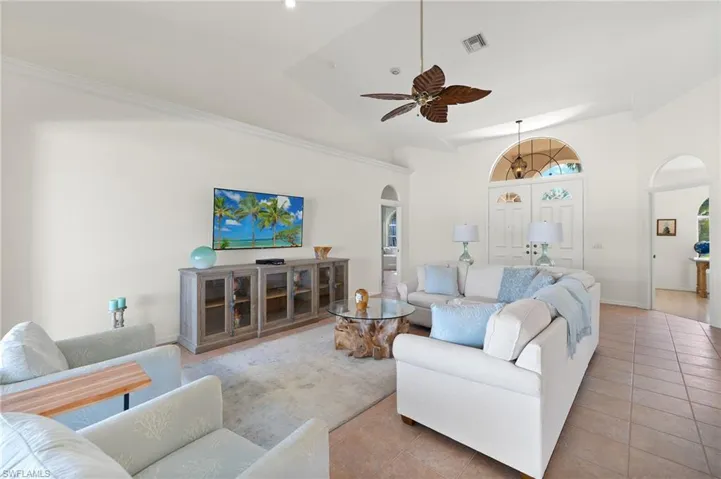 Tiled living room featuring high vaulted ceiling and ceiling fan
