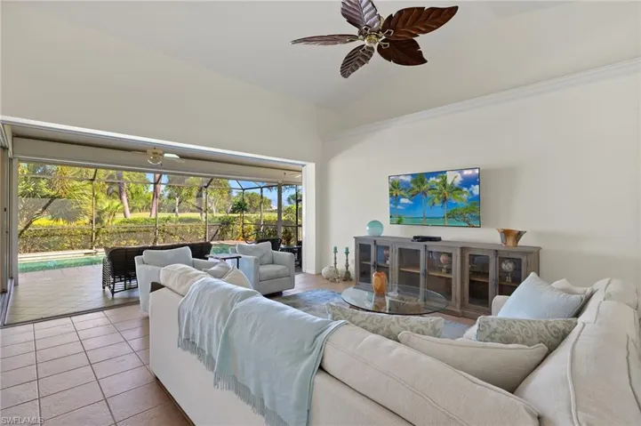 Living room featuring light tile patterned floors, high vaulted ceiling, a wealth of natural light, and ceiling fan
