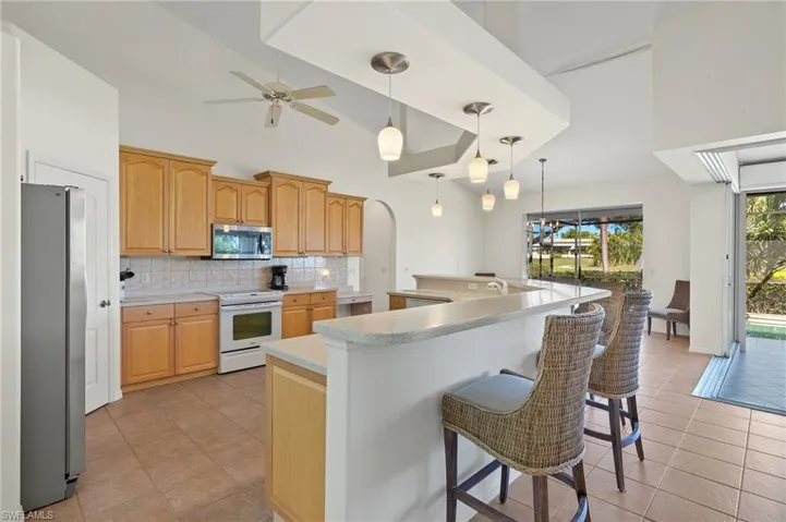 Kitchen with a kitchen breakfast bar, ceiling fan, stainless steel appliances, and an island with sink