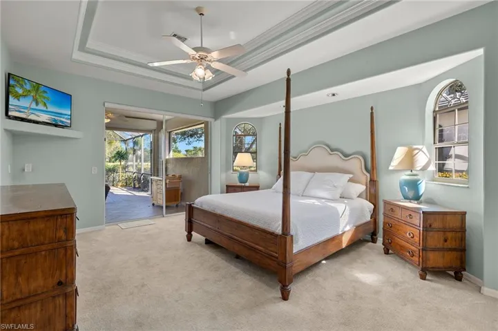 Carpeted bedroom with access to outside, ceiling fan, a tray ceiling, and ornamental molding
