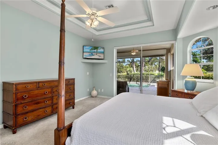 Bedroom featuring access to exterior, light carpet, ornamental molding, a tray ceiling, and ceiling fan